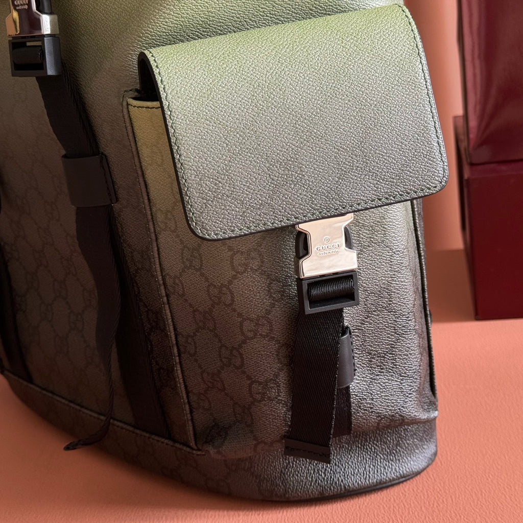 Side detail of monogram mini backpack with front flap, clasp, and black strap