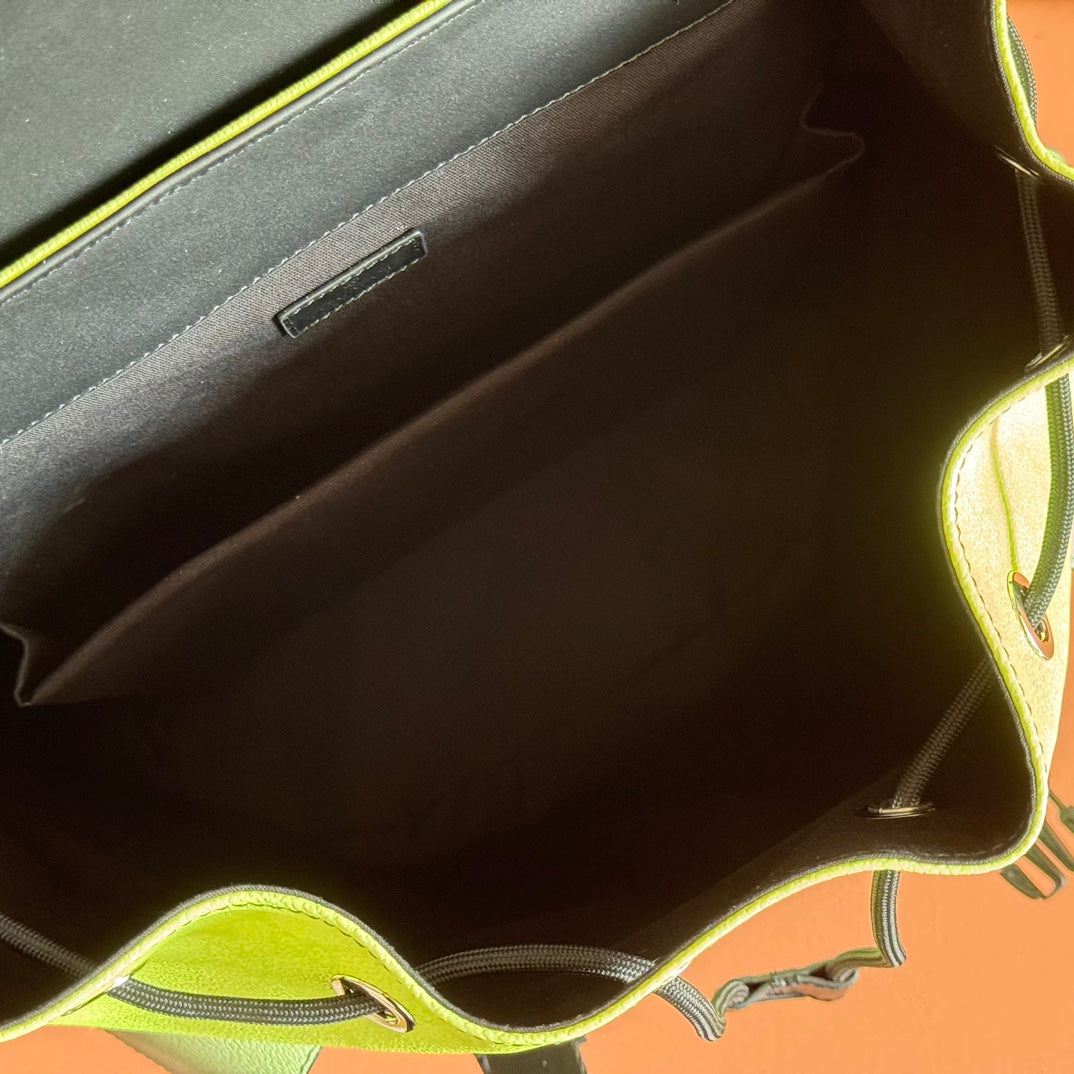 Interior view of green mini backpack opening with dark lining and side pocket