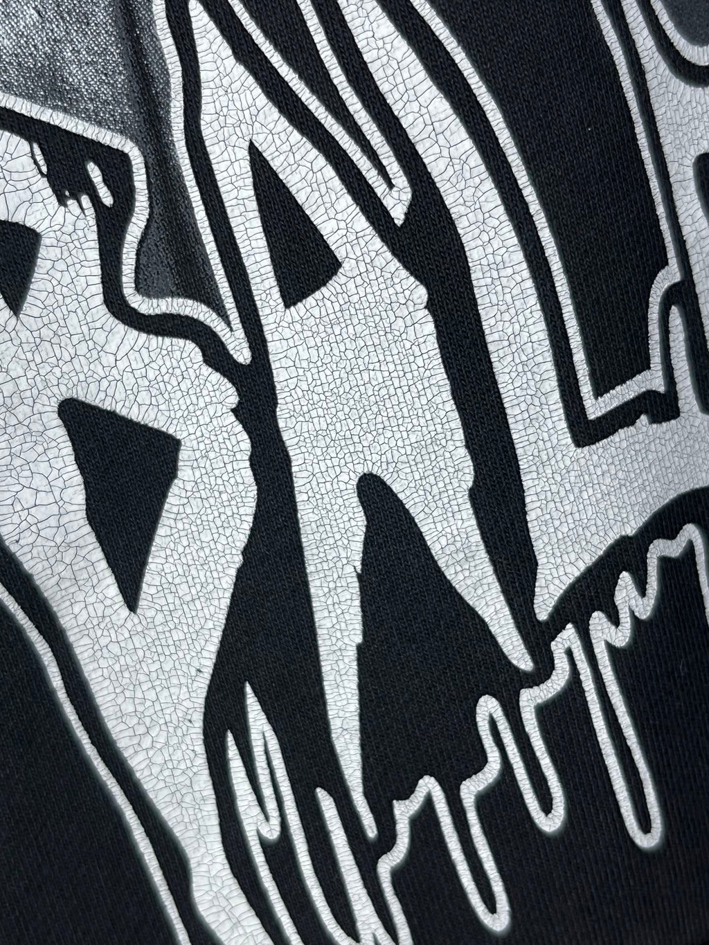 Dark hoodie close-up of white graffiti-style lettering print.