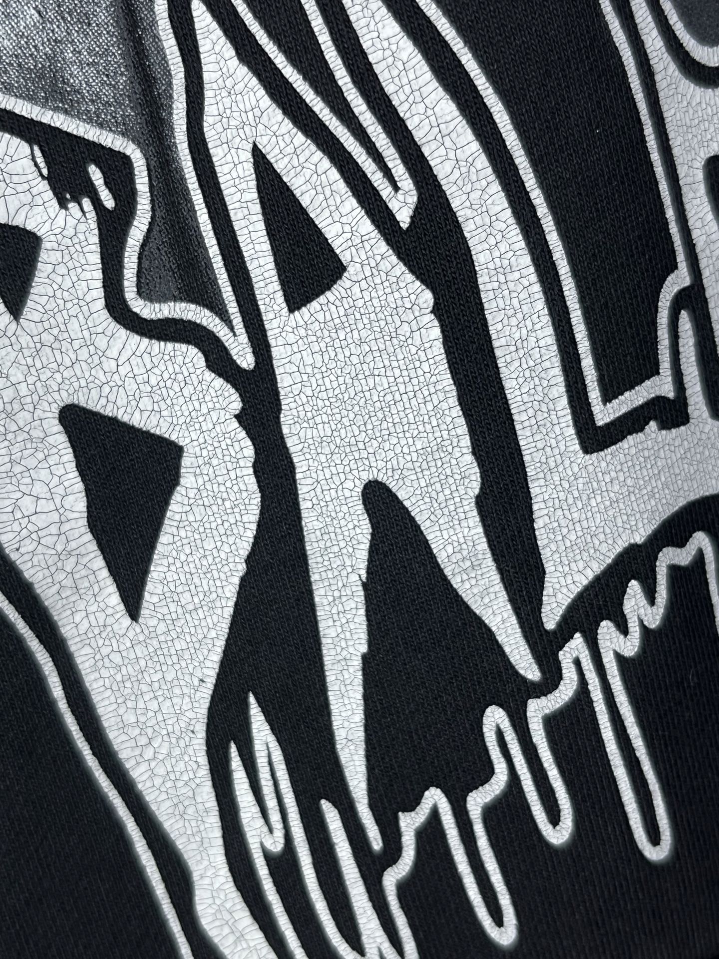 Dark hoodie close-up of white graffiti-style lettering print.