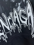 Dark hoodie with oversized white graffiti-style logo print on the chest.