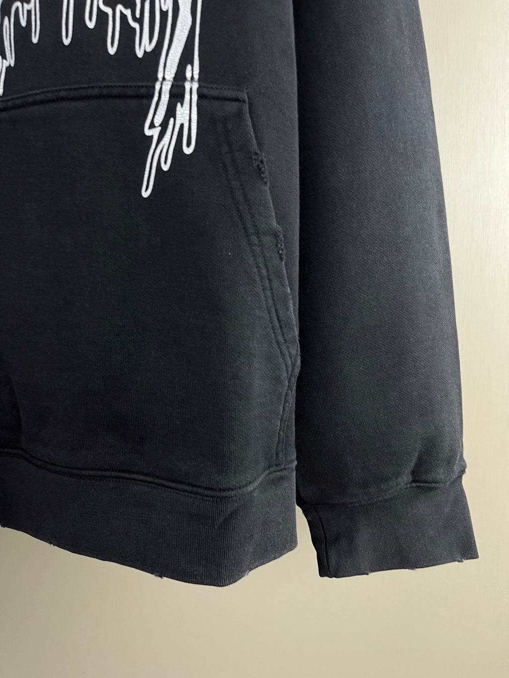 Dark hoodie front pocket area with drips graphic and ribbed cuff hem.