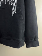 Dark hoodie front pocket area with drips graphic and ribbed cuff hem.