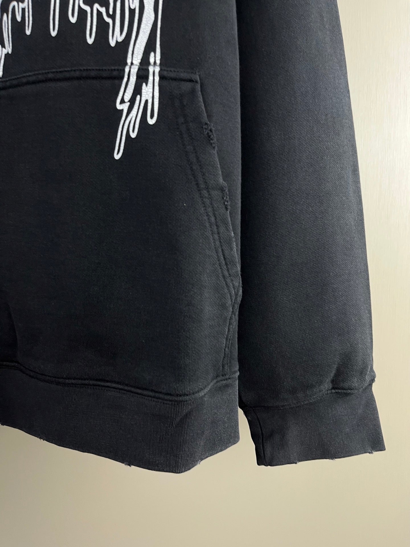 Dark hoodie front pocket area with drips graphic and ribbed cuff hem.