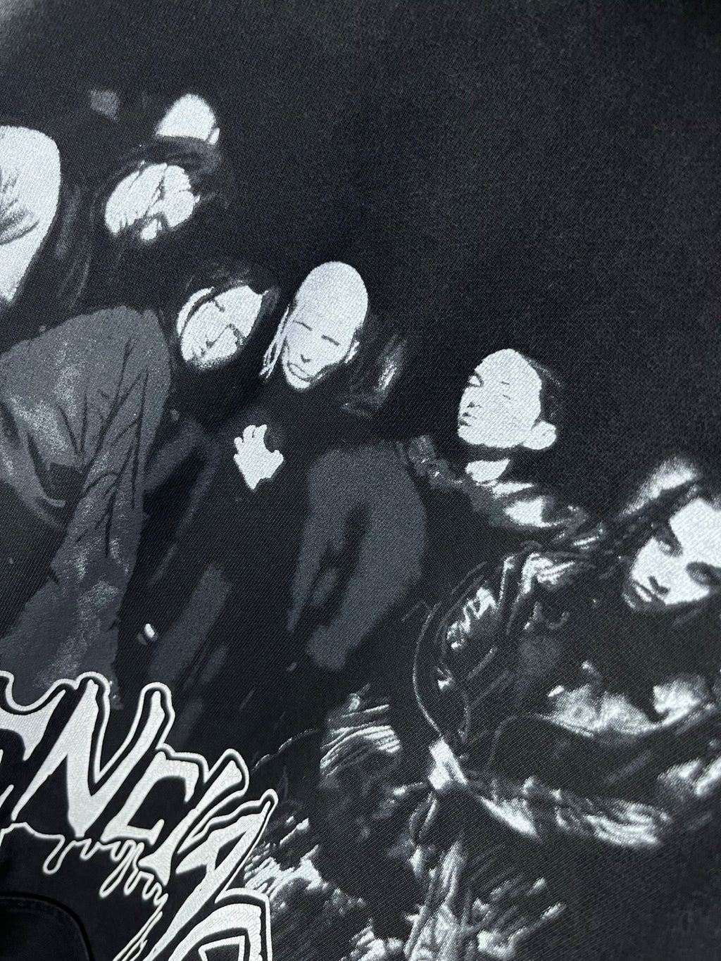 Dark hoodie close-up with large black-and-white crowd graphic print.