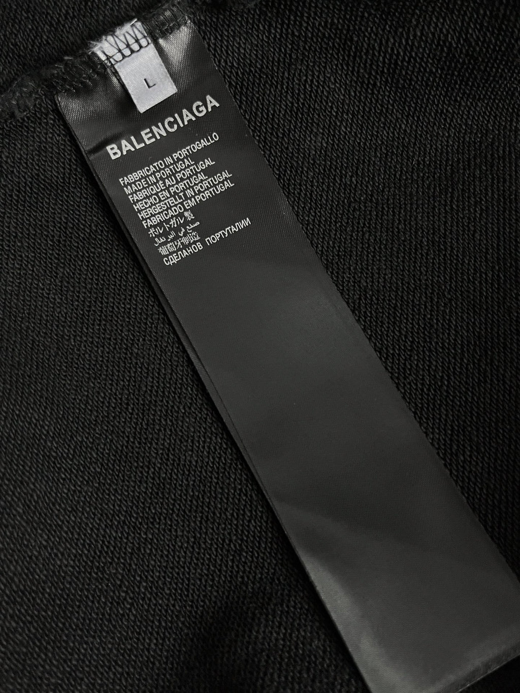 Dark hoodie fabric with inner neck label and care text.