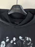 Dark hoodie close-up at hood and neckline with inner logo label and crowd graphic print.