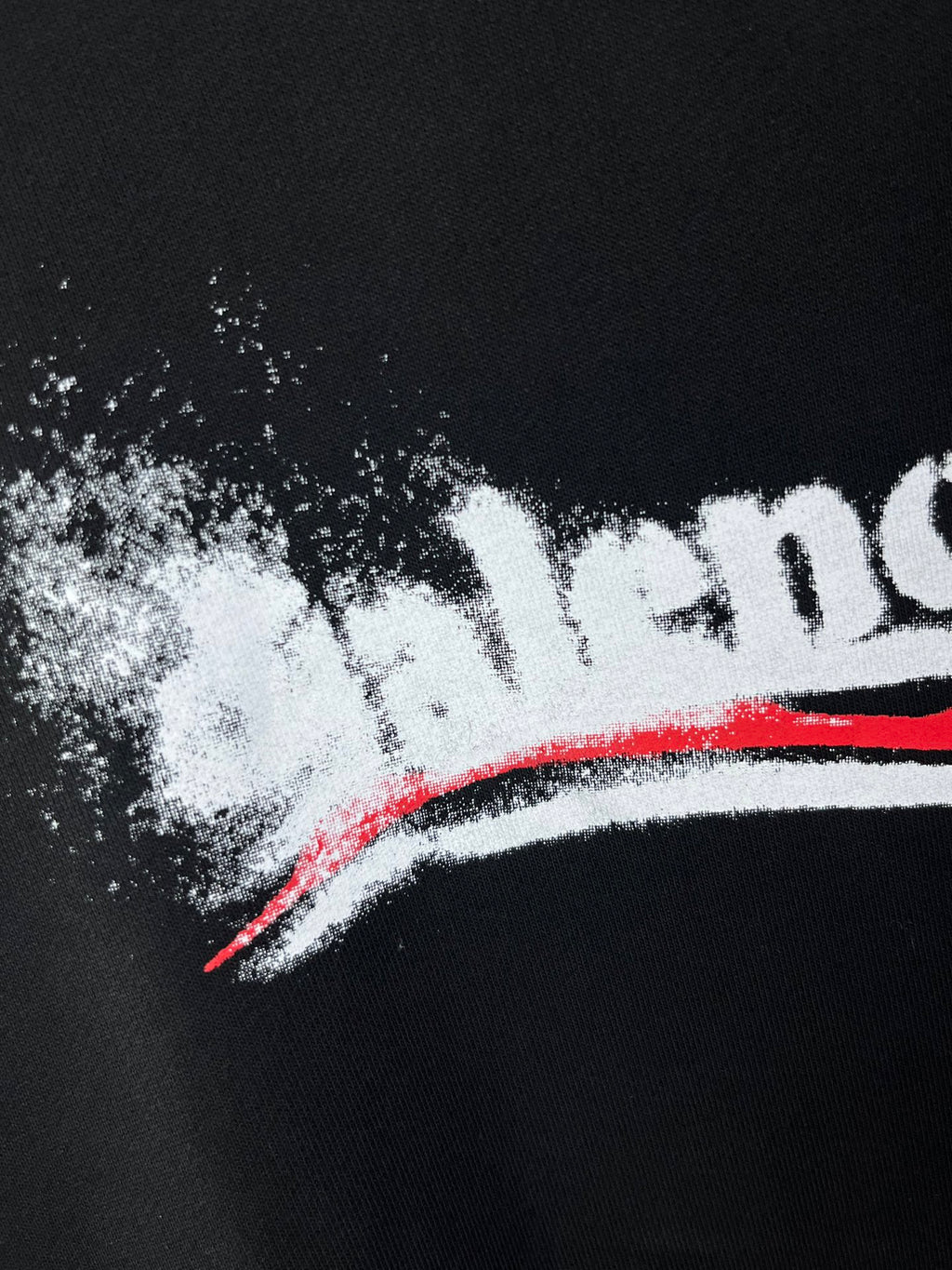 Close-up of Balenciaga logo print on dark hoodie fabric