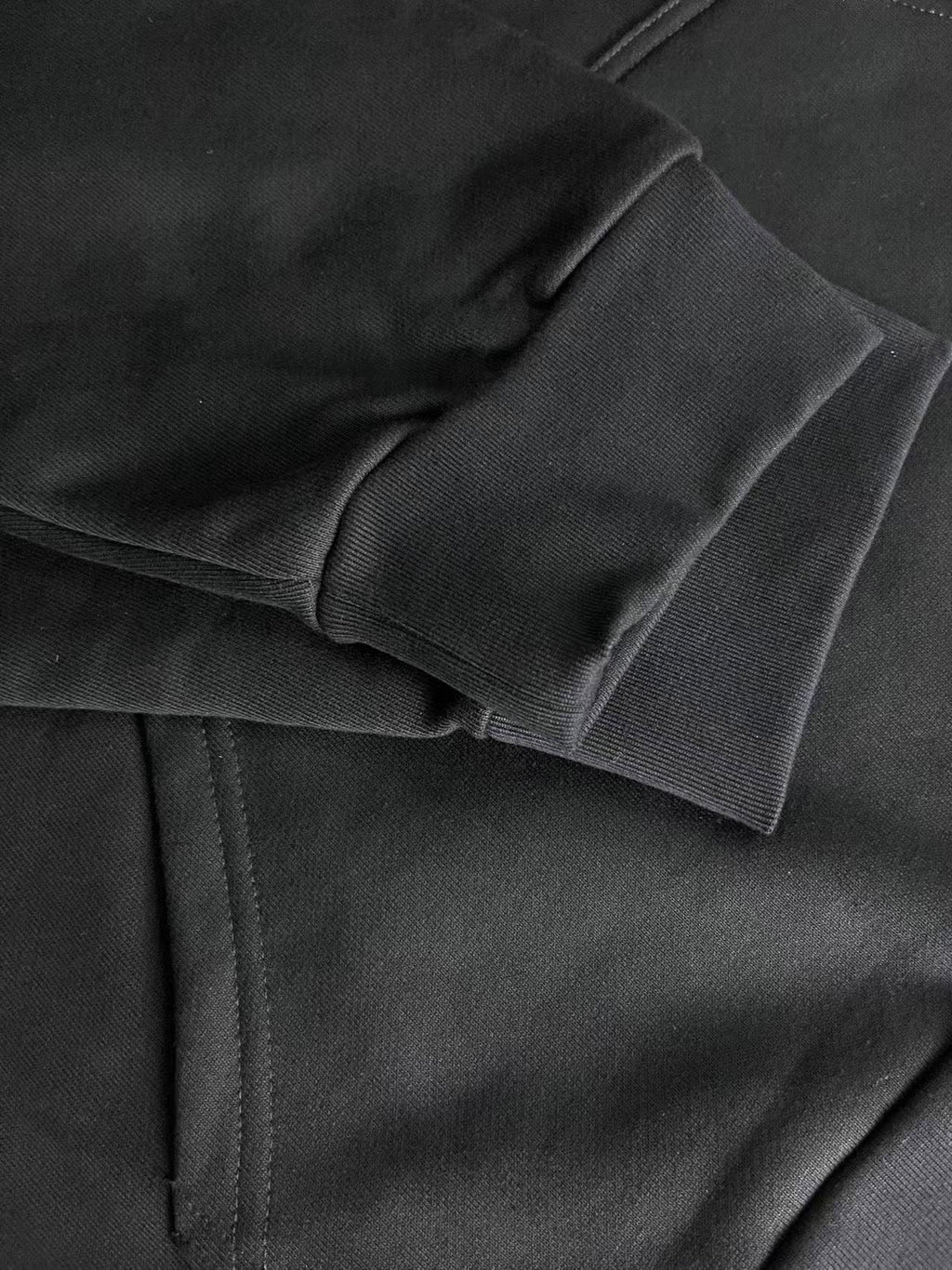 Dark hoodie fabric close-up with layered hood seam and stitching