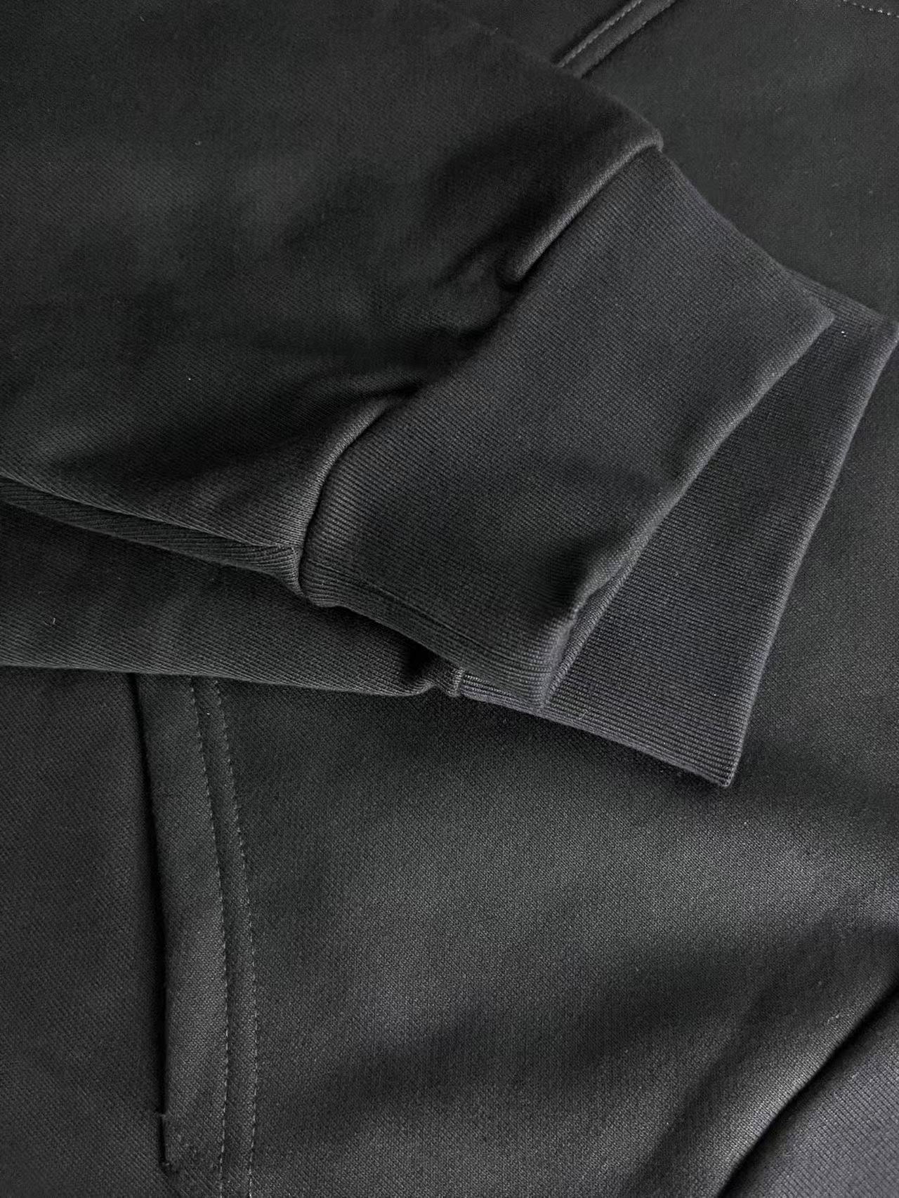 Dark hoodie fabric close-up with layered hood seam and stitching