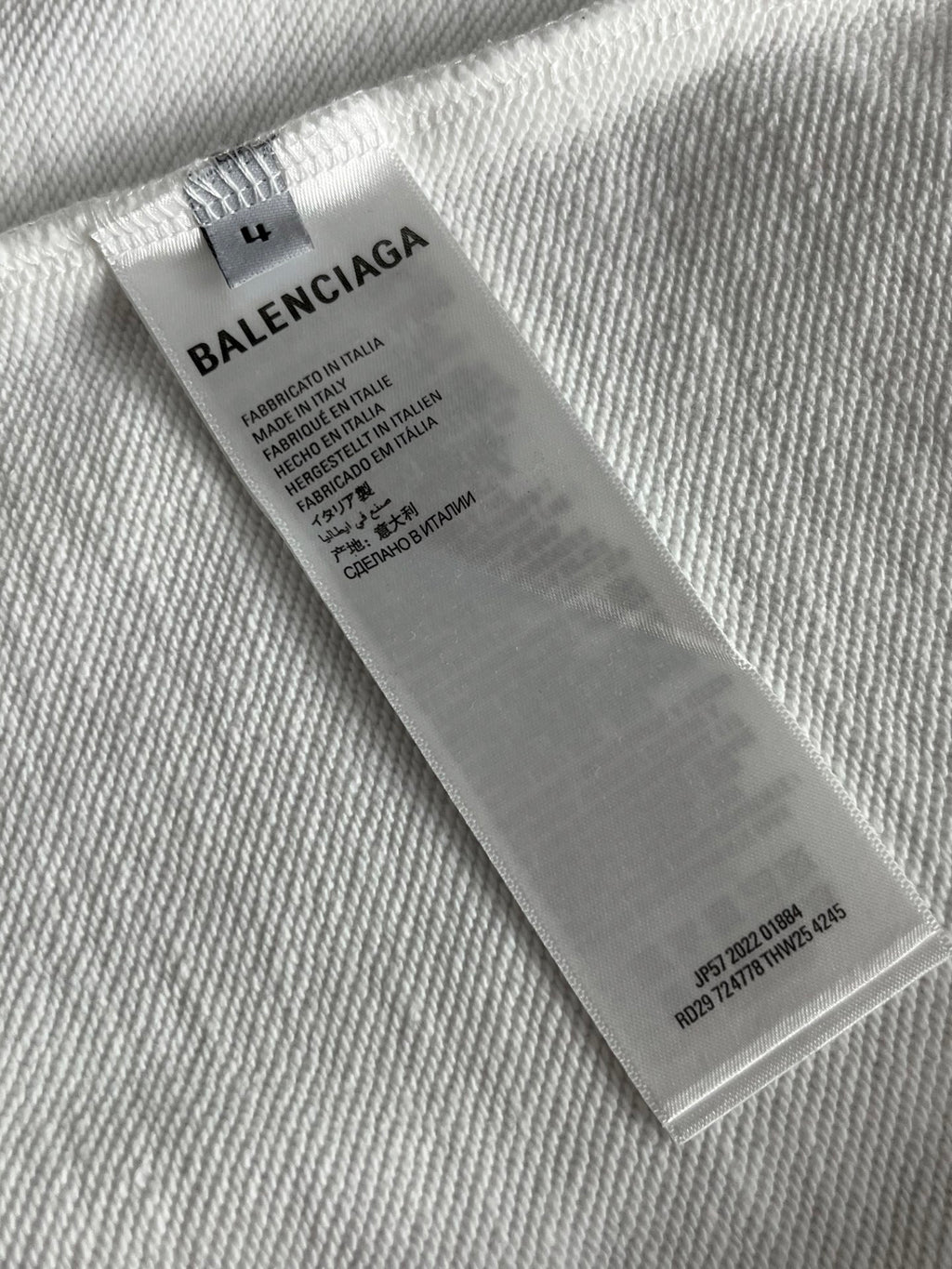 White sweatshirt care label tag with Balenciaga branding and size info