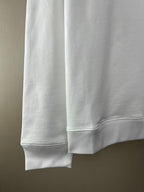 White sweatshirt with long sleeves, ribbed cuffs, and curved hem