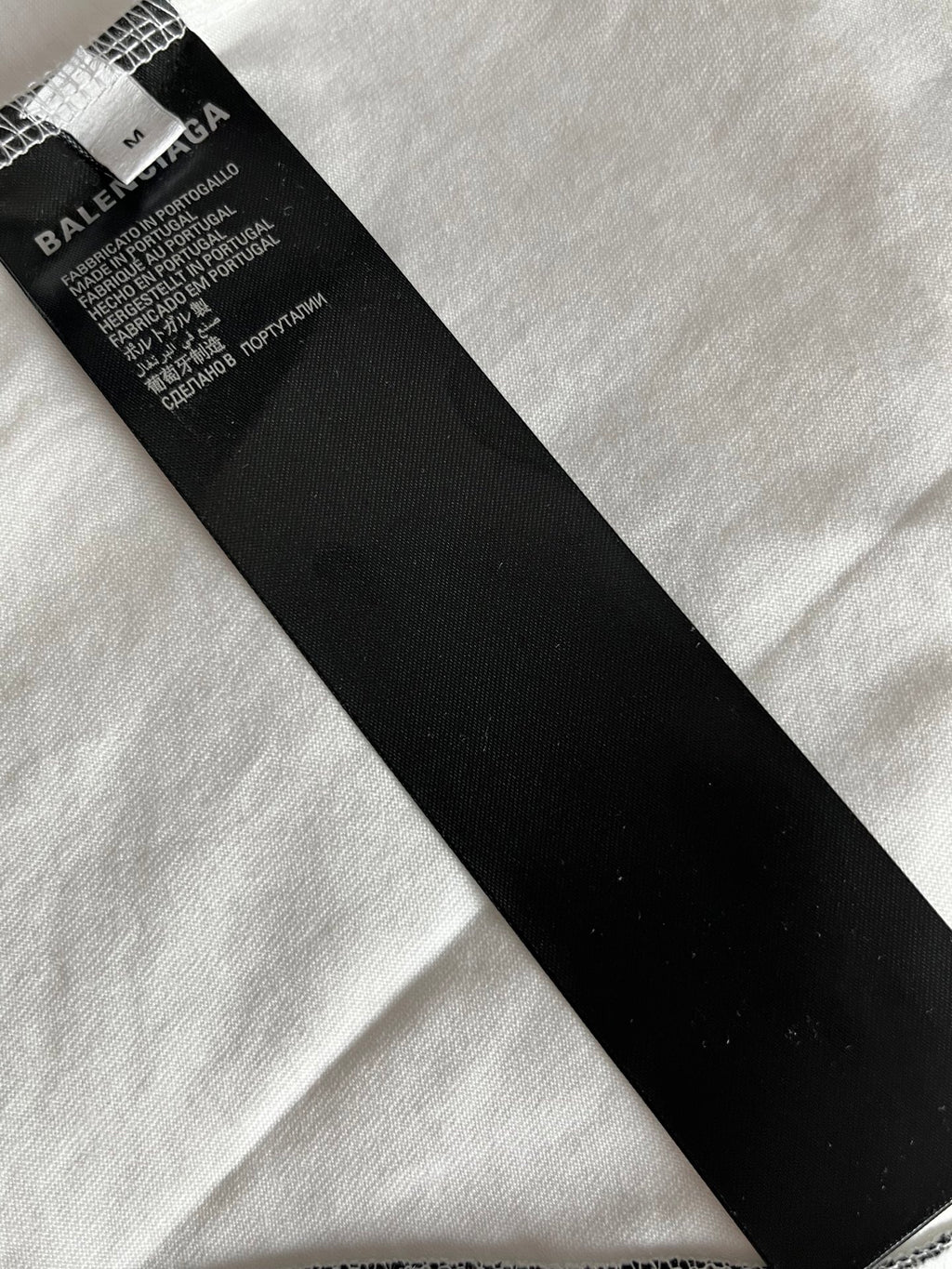 Black fabric care label at neckline of white jersey