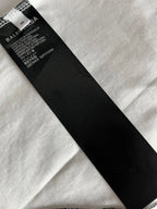 Black fabric care label at neckline of white jersey