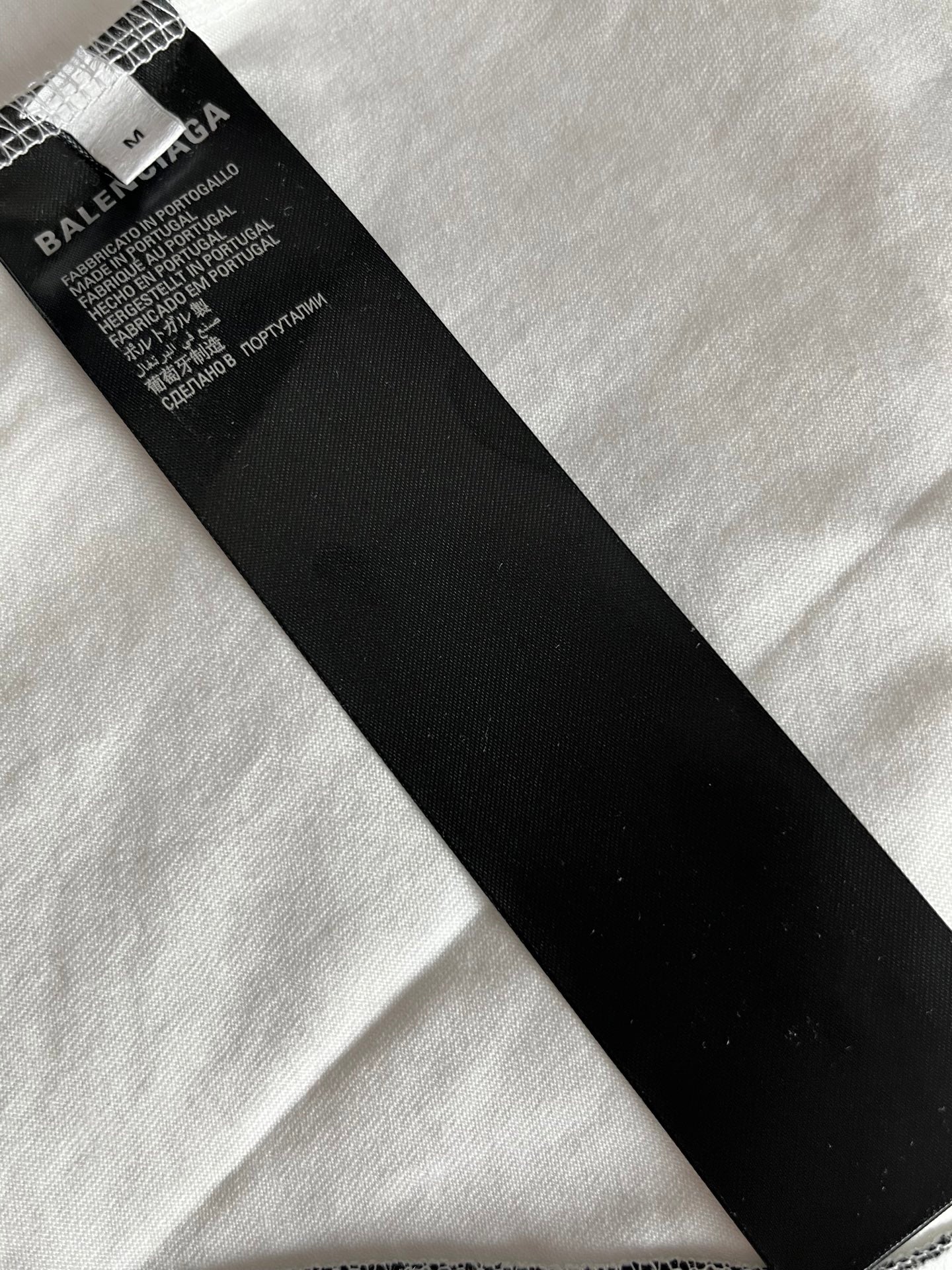 Black fabric care label at neckline of white jersey