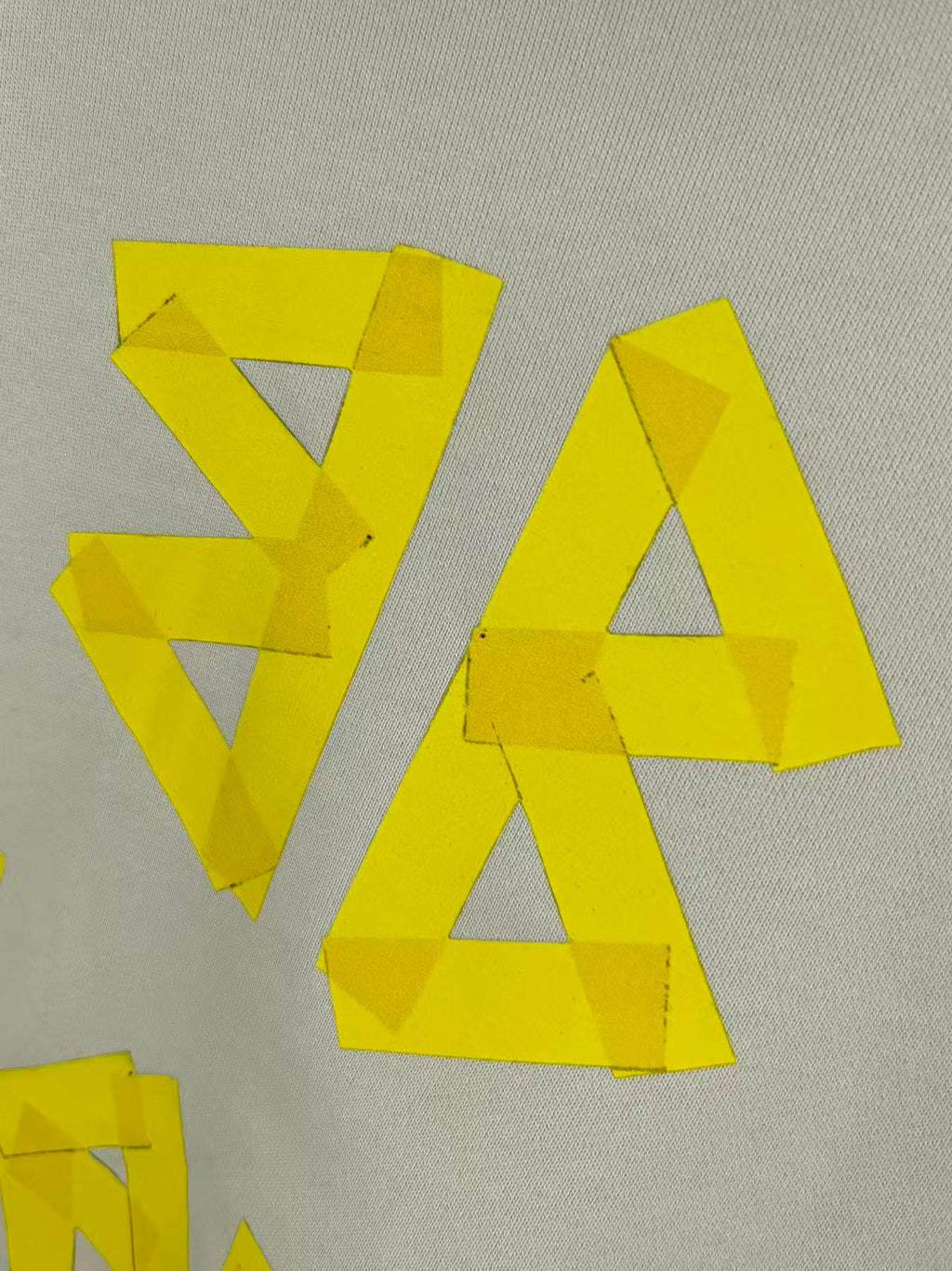 Close-up of yellow logo lettering on white fabric