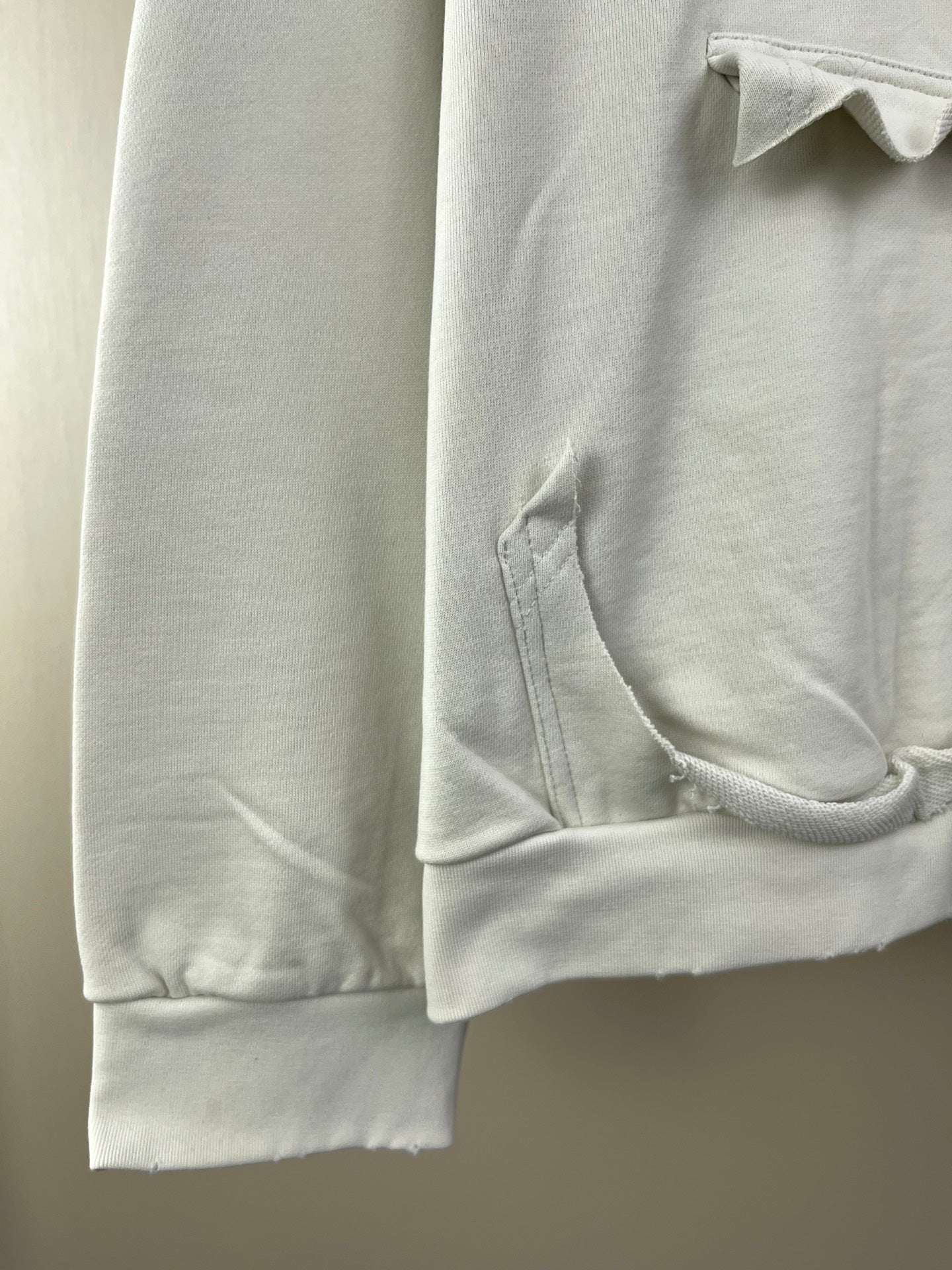 White hoodie sleeve with ribbed cuff and stitched pocket opening