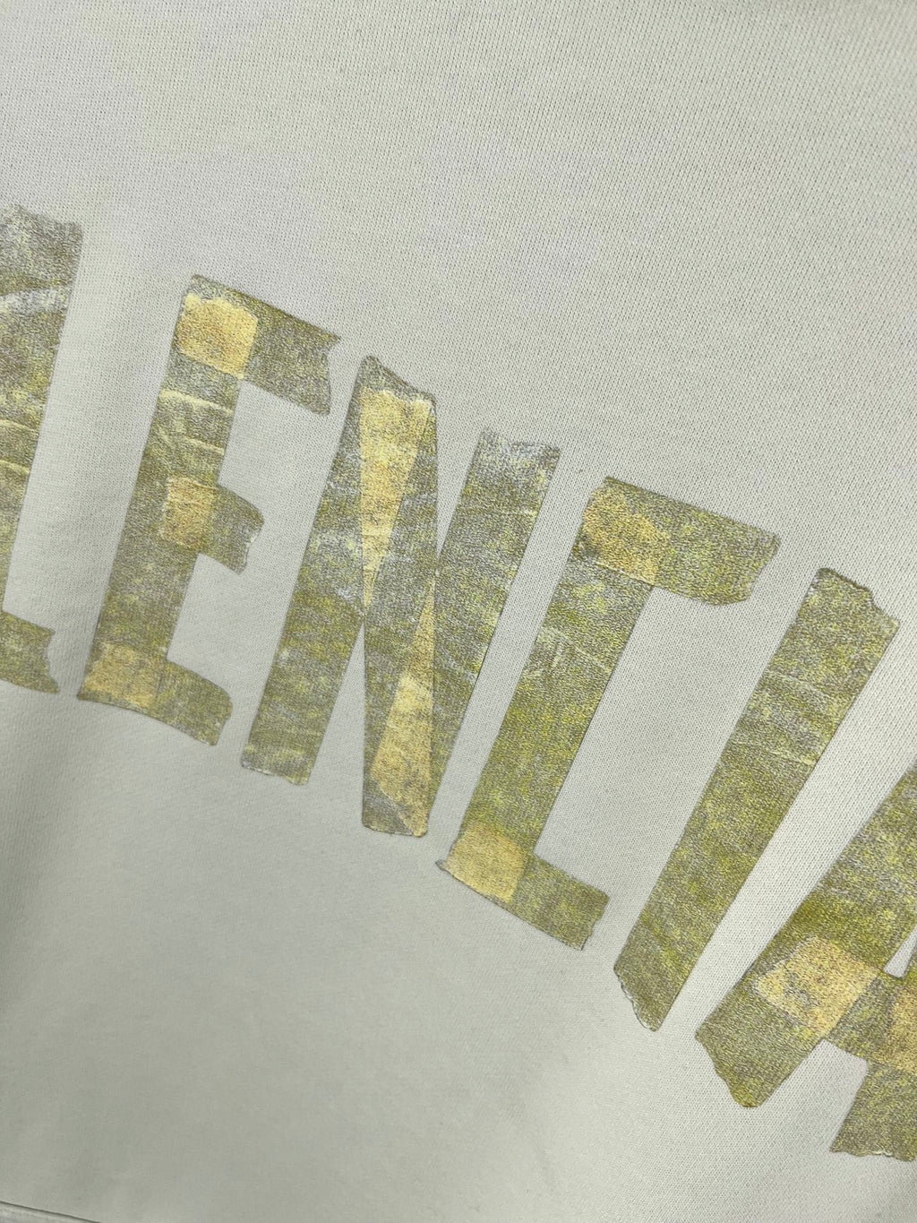 Close-up of gold glitter-style 'IDENTIAL' lettering on white hoodie