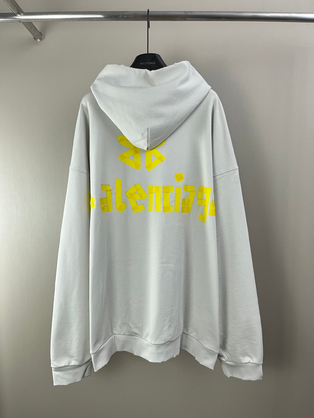 White long-sleeve hoodie with hood and yellow back graphic text and symbol