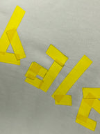 Close-up of yellow logo lettering and geometric blocks on white fabric