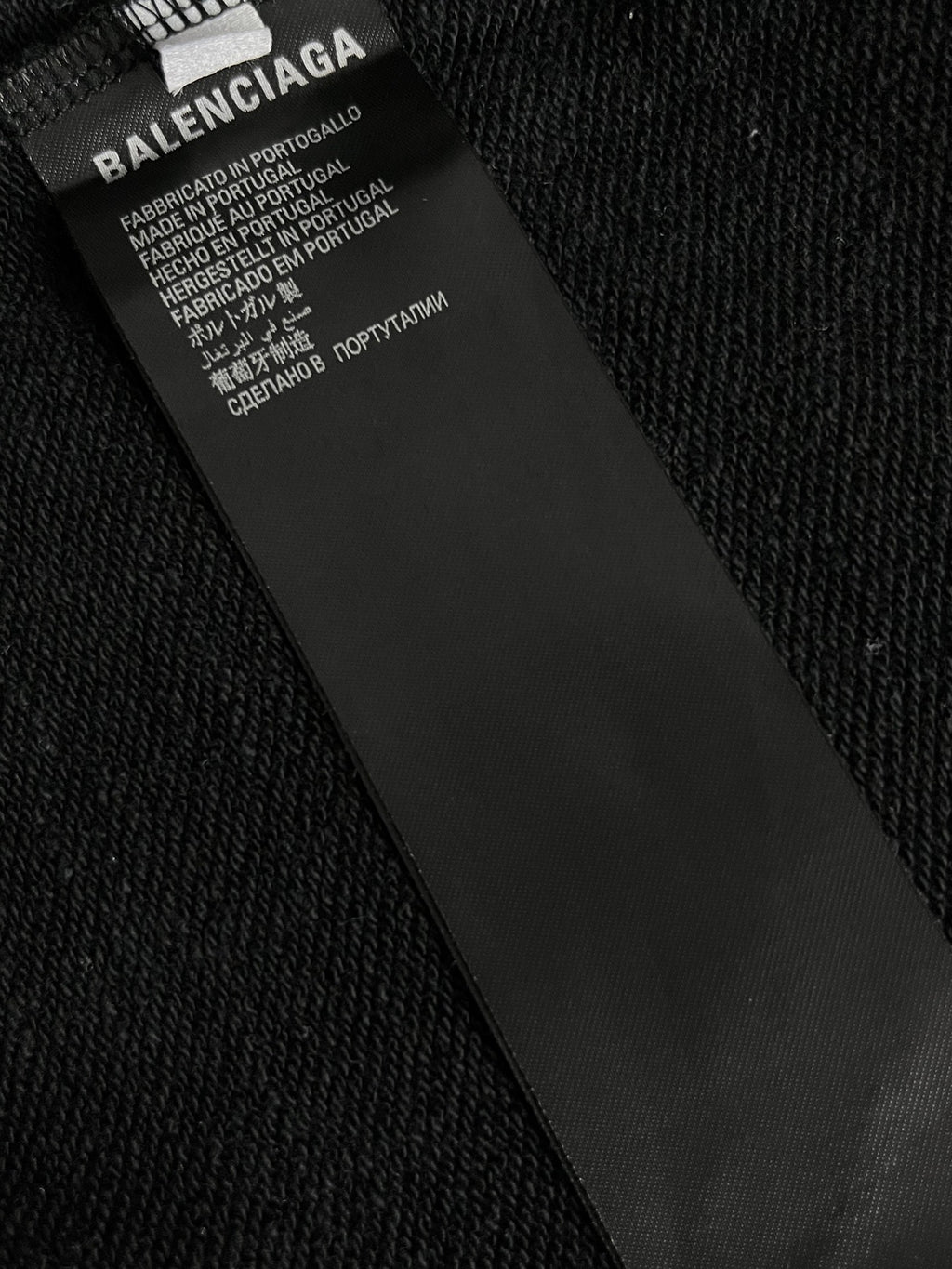 Inside neck label on black hoodie with text and care information