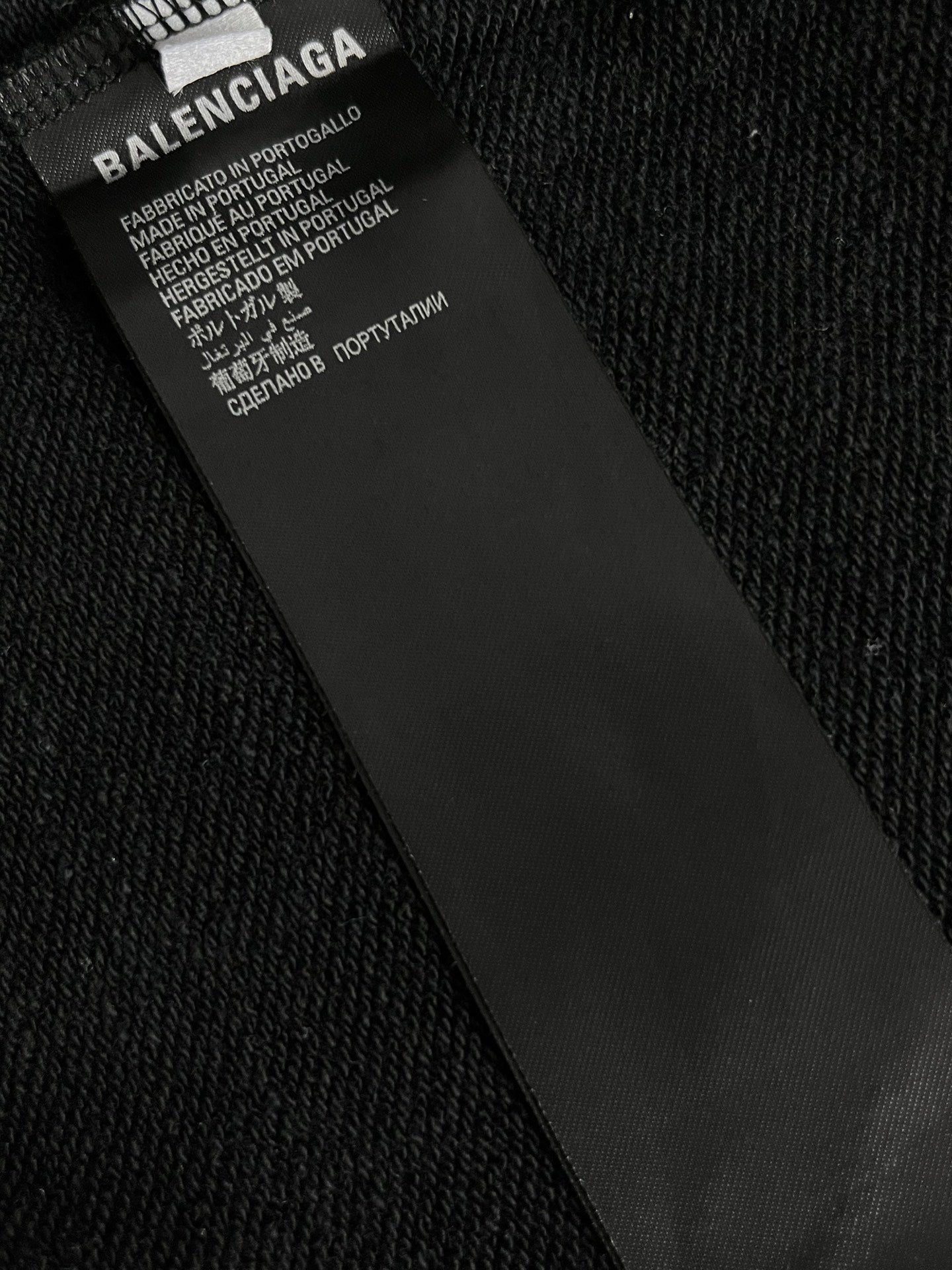 Inside neck label on black hoodie with text and care information