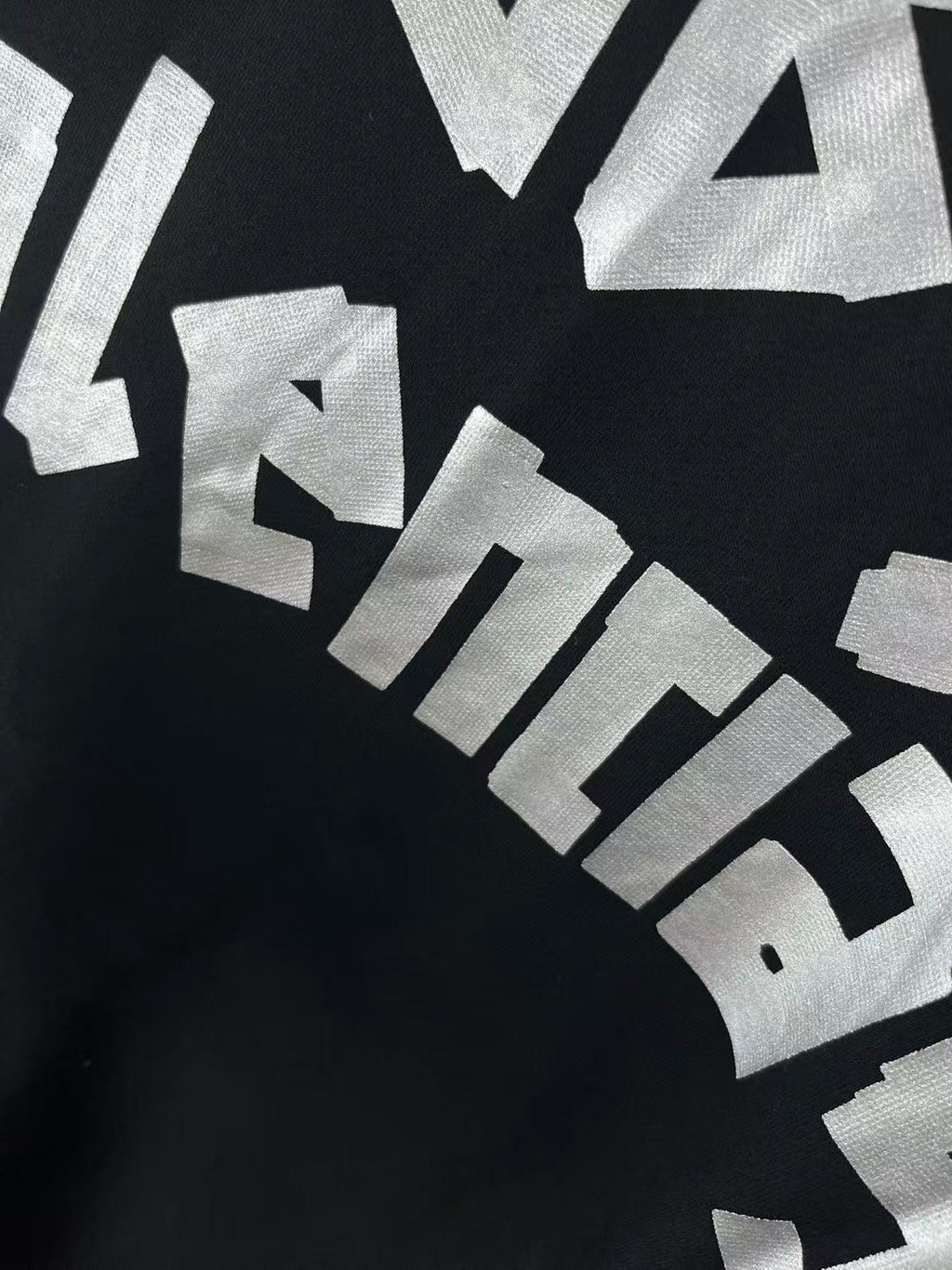 Close-up of angled white graphic lettering on dark hoodie