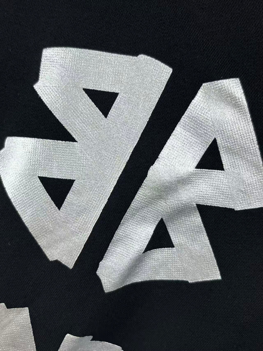 Close-up of large white graphic letters on dark hoodie fabric