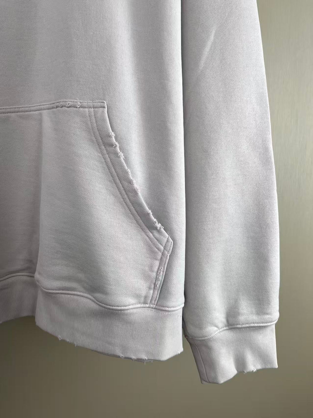 White hoodie pocket and hem close-up with stitched seams and ribbed cuffs
