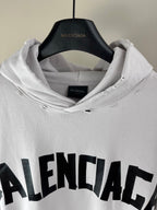 White hoodie close-up with hood, drawstrings, and BALENCIAGA logo on chest