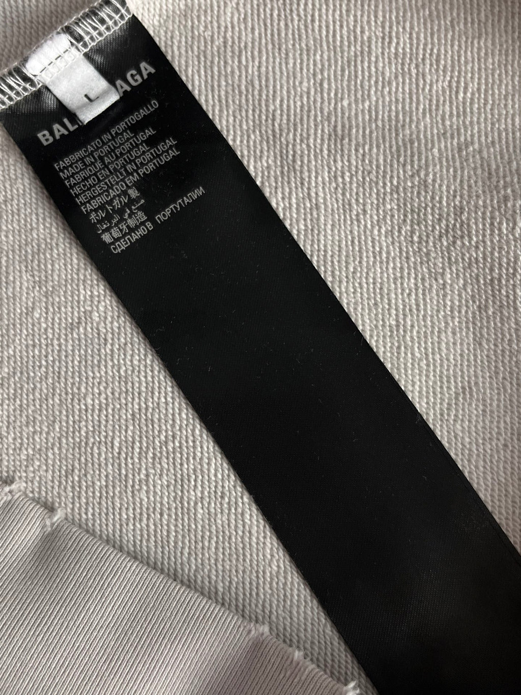 Black size tag inside hoodie with BALENCIAGA text on white fabric