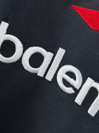 Navy T-shirt fabric close-up with white balenciaga wordmark and red emblem