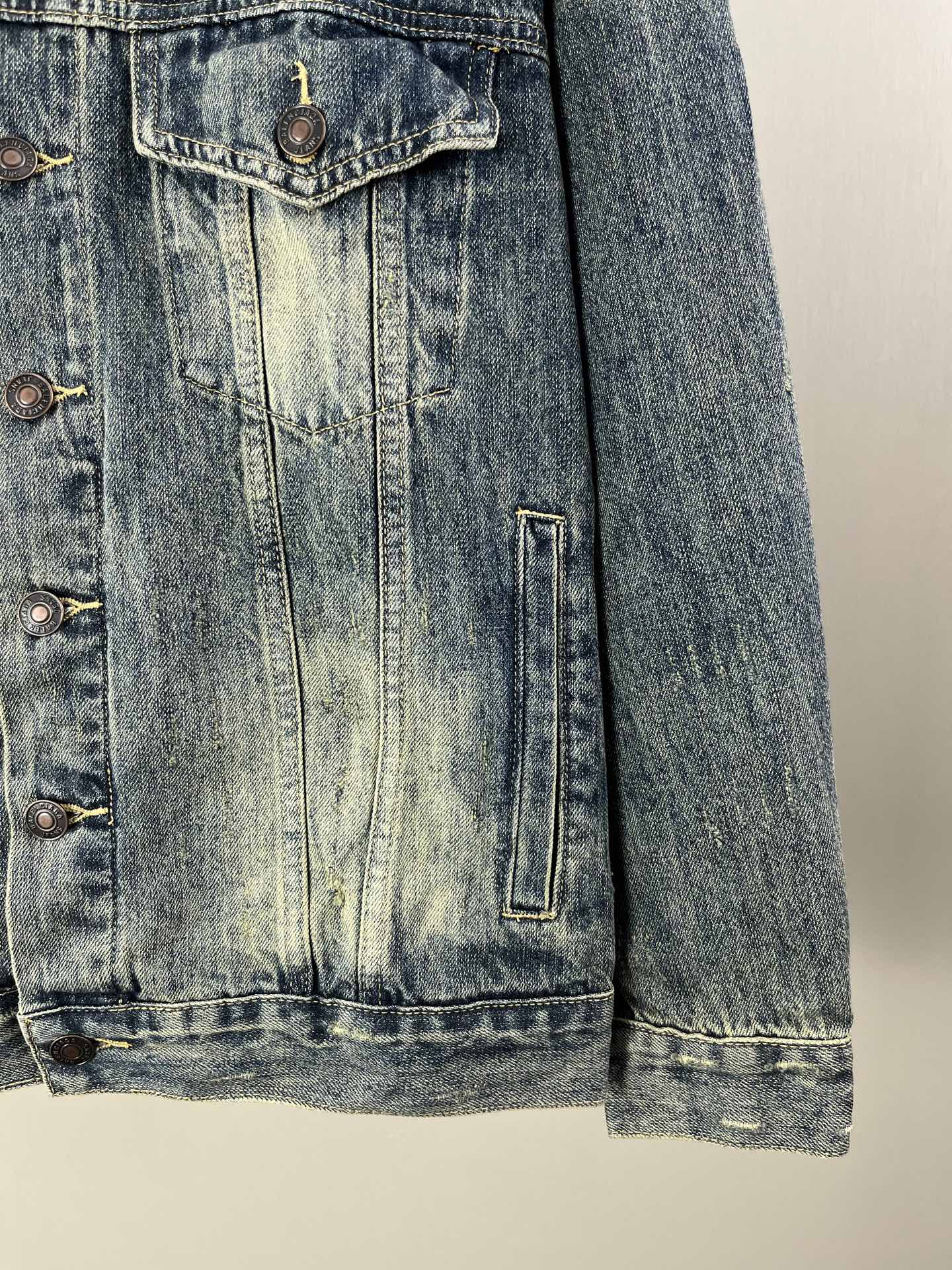 Washed blue denim jacket side seam and flap pockets with metal buttons