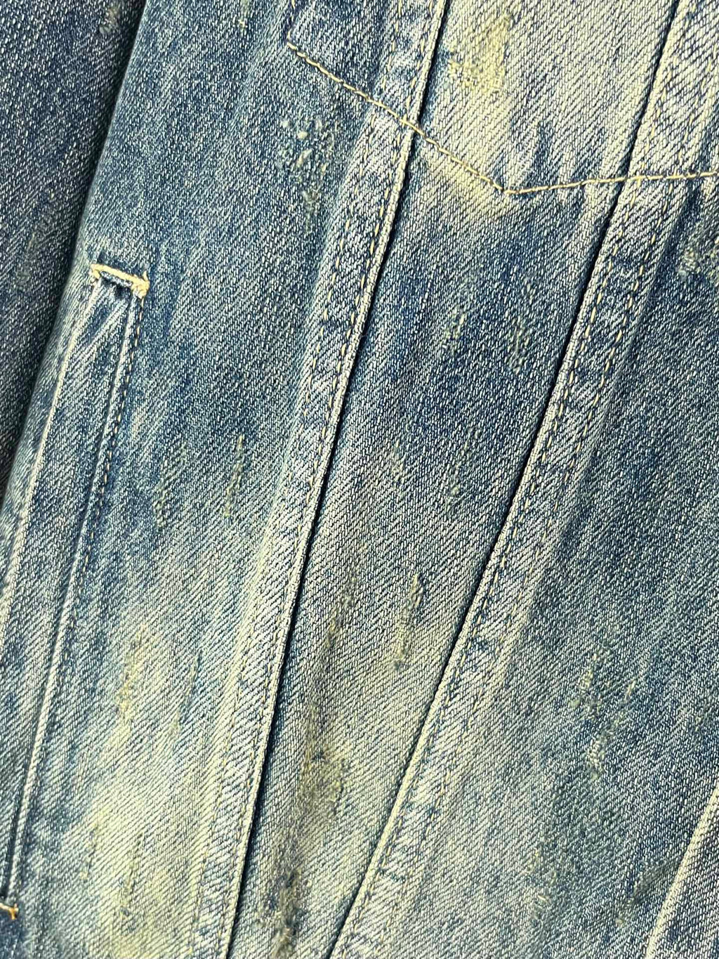 Washed blue denim jacket front panel with stitched seams and distressed finish
