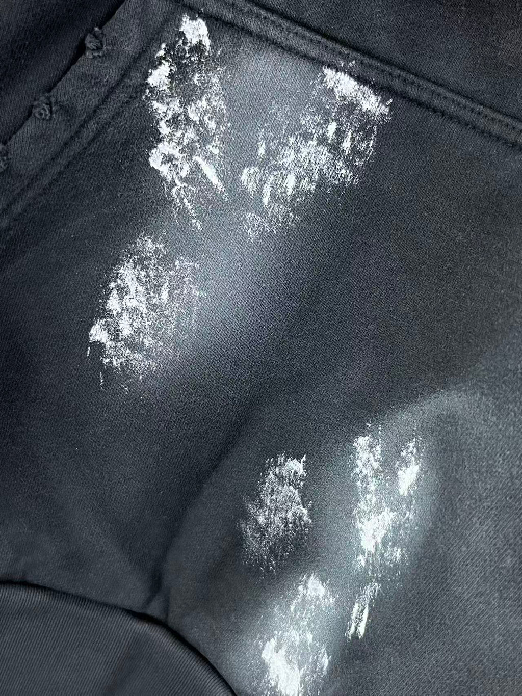 Close-up of metallic logo patch on long hoodie pocket area