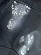 Close-up of metallic logo patch on long hoodie pocket area