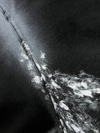 Close-up of metallic logo print on long hoodie seam and pocket edge