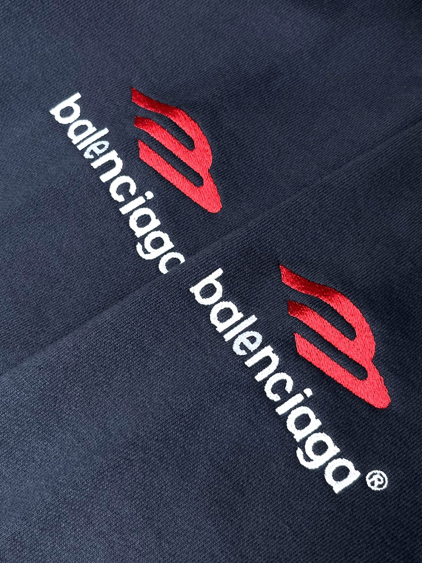 Navy hoodie sleeve with red emblem and white Balenciaga text