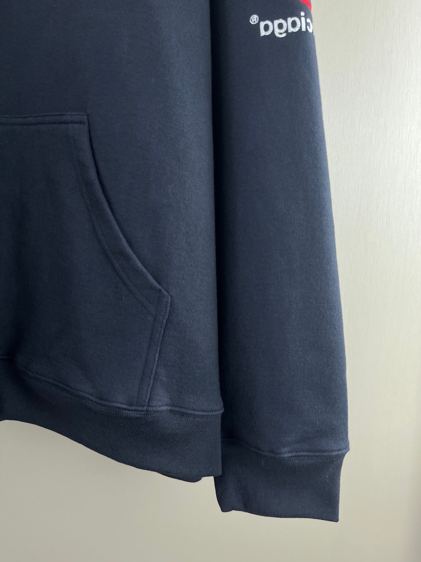 Navy hoodie side view with kangaroo pocket seam and ribbed hem
