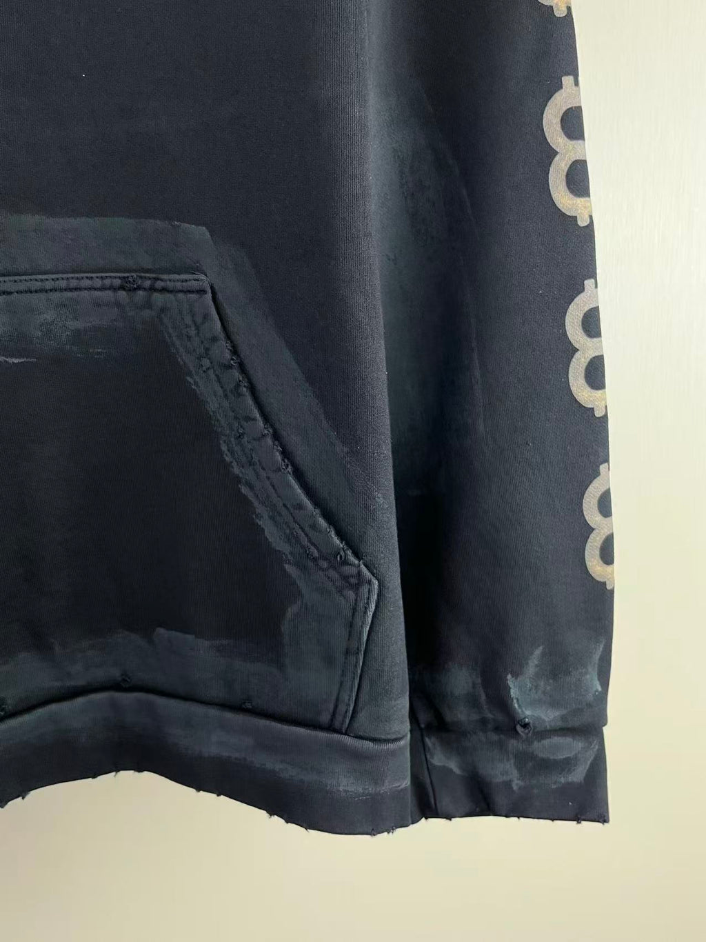 Balenciaga hoodie hem and pocket corner; dark sleeve shows repeated BB logo marks