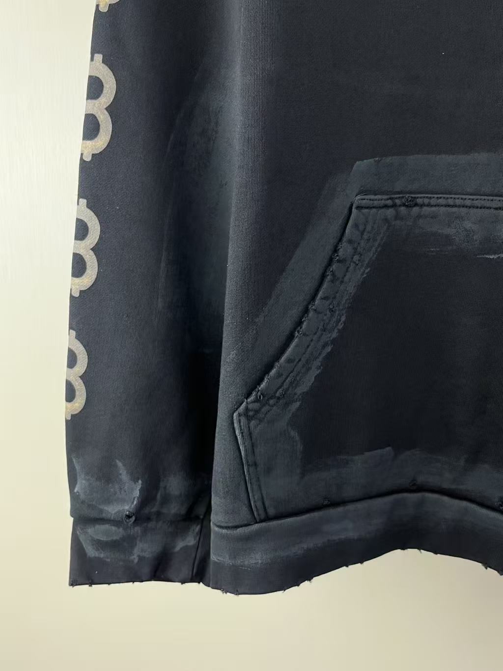 Balenciaga hoodie side view: kangaroo pocket and dark sleeve cuff with repeated BB text