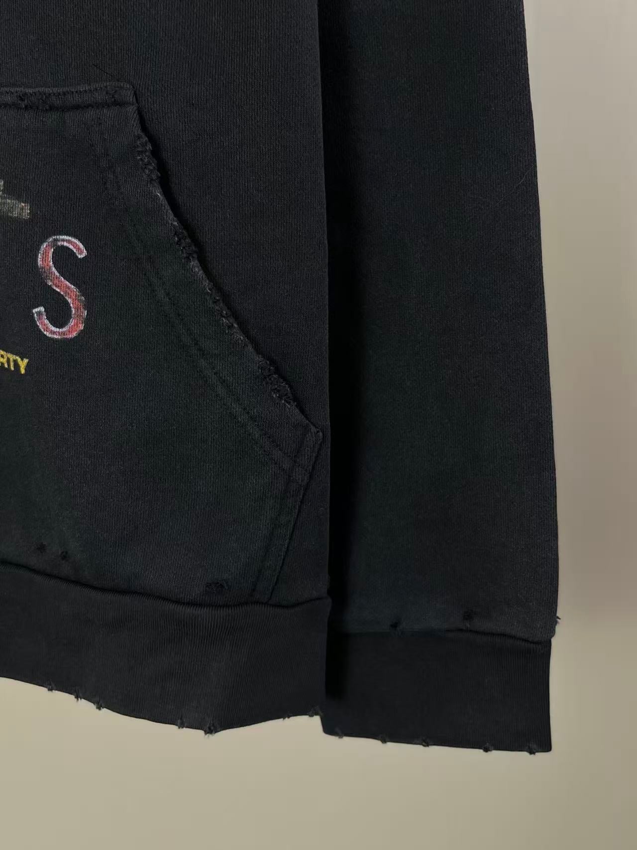 Balenciaga dark hoodie pocket seam and sleeve hem detail with partial red letter graphic