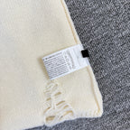 Cream knit sweater sleeve with size label and frayed embroidered trim