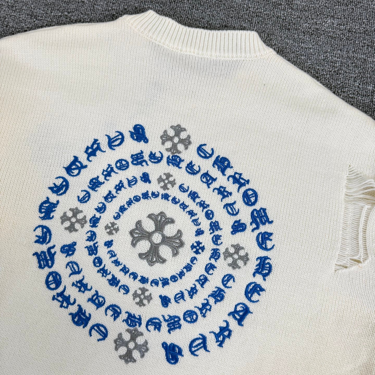Cream knit sweater back showing blue circular motif embroidery