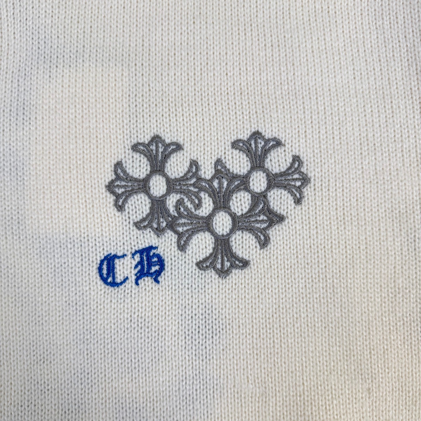 Cream knit sweater chest graphic with gray floral motif and blue accent