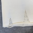 Cream knit sweater hem with frayed lace-like embroidery detail