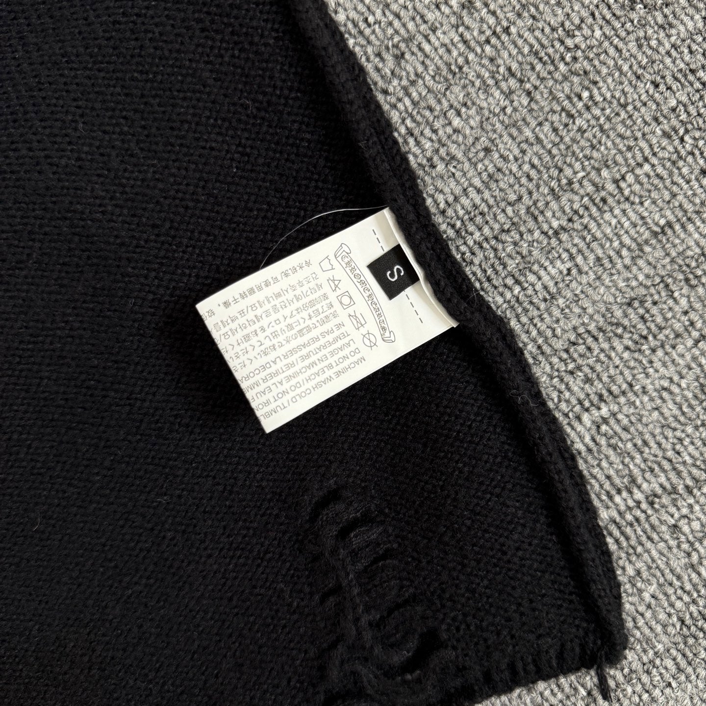 Long-sleeve sweater neck label tag on black knit
