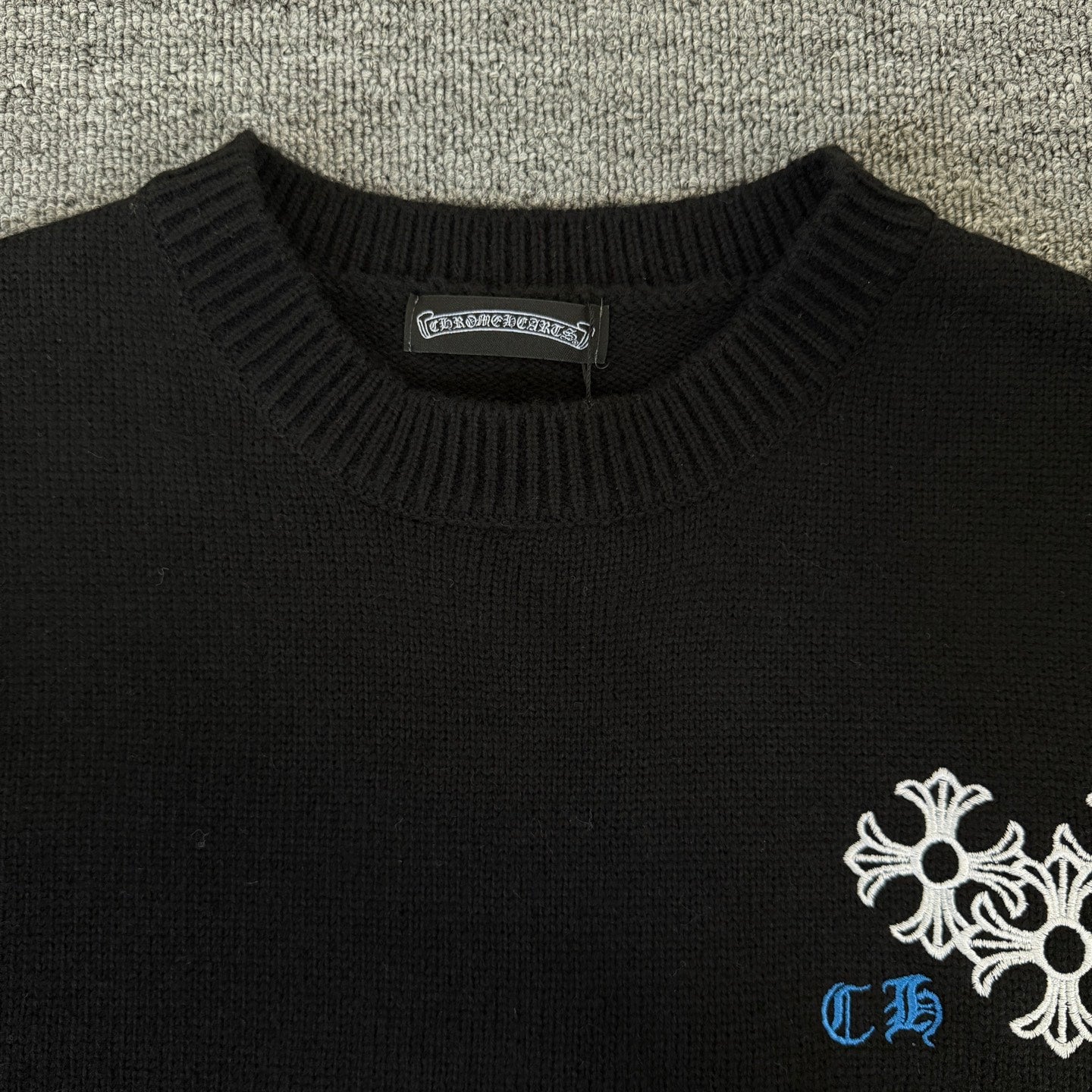 Black long-sleeve sweater with ribbed crew neck and white-blue chest embroidery
