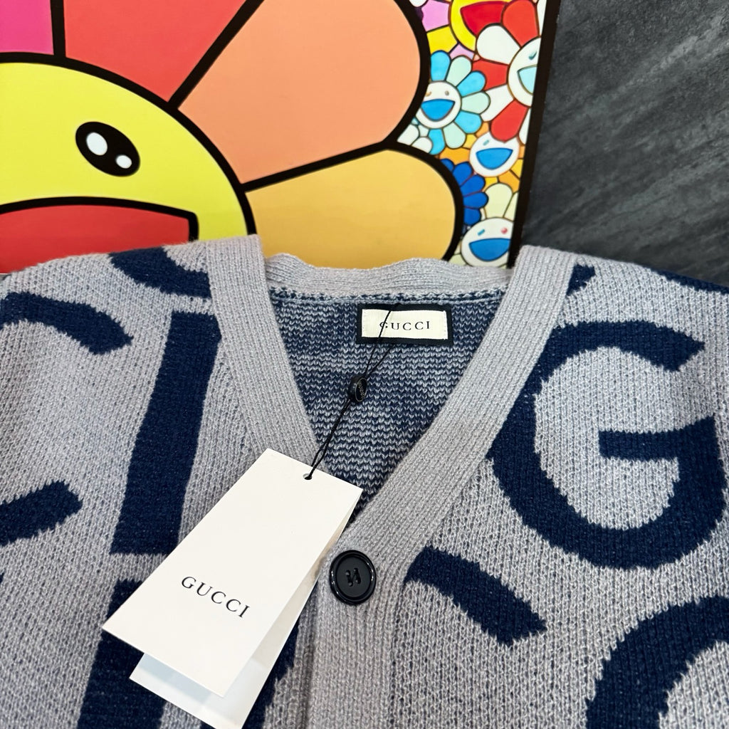 Kids cardigan neckline close-up, light gray knit with navy Gucci pattern and buttons