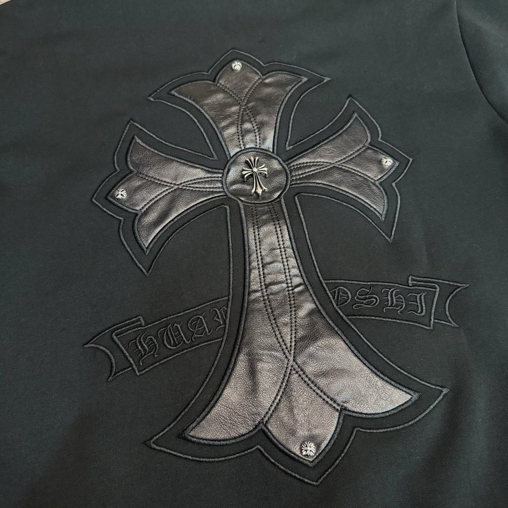 Black hoodie close-up of large metallic bow-and-cross emblem